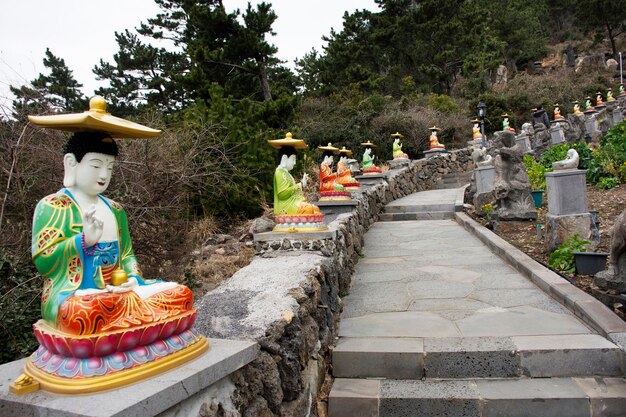 La figure colorée du dieu chinois et la statue de bouddha ange divinité sur des escaliers en pierre vont à la montagne de Sanbangsa pour les voyageurs coréens voyagent visiter le respect prier dans le temple de Sanbangsa à Jeju do Corée du Sud