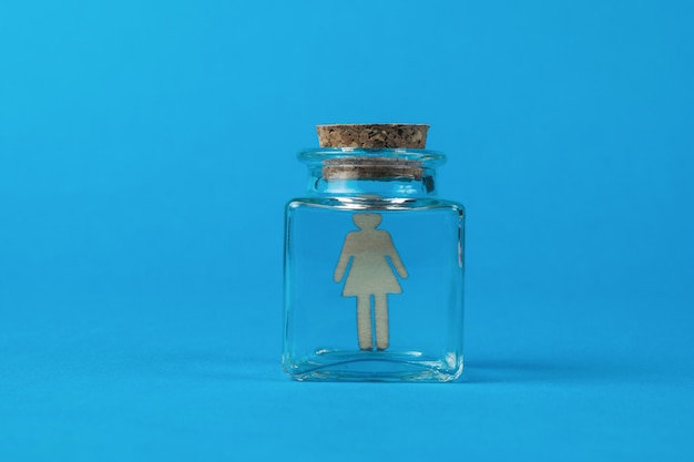 Une figure féminine en bois dans un flacon en verre fermé.