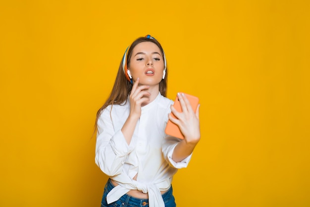 Figure de genou de jeune belle femme caucasienne écoutant de la musique avec des écouteurs dansant en souriant