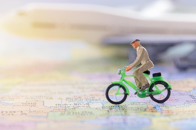 Figure homme d'affaires à vélo sur la carte du monde avec fond d'avion blanc flou