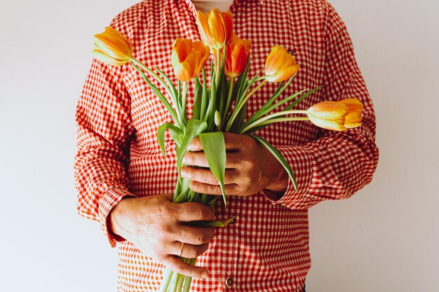 figure méconnaissable de l'homme en chemise à carreaux rose, avec bouquet de tulipes dans les mains