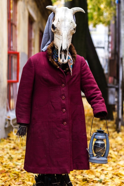 Une figure sinistre dans un manteau de vieille femme et avec un crâne d'animal au lieu d'une tête avec une lanterne à la main
