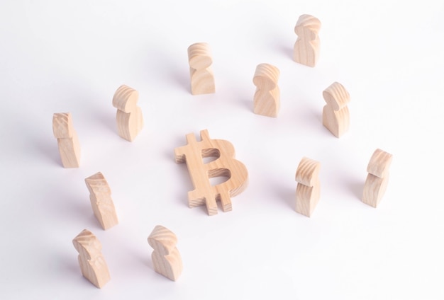 Figures en bois de personnes sont debout près d&#39;un bitcoin sur un fond blanc