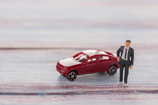 Figures d'homme d'affaires debout sur le sol avec une voiture floue