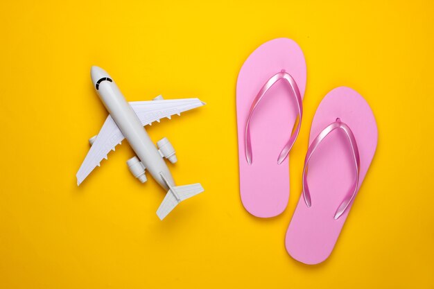 Figurine d'avion, tongs sur un jaune. Vacances à la plage.