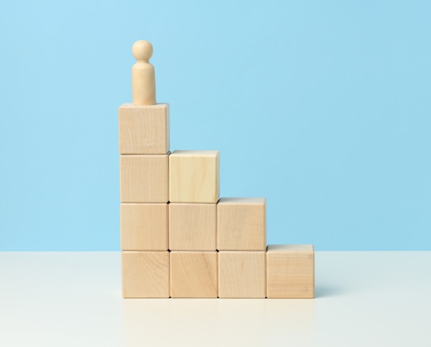 Figurine en bois d'un homme sur des cubes en bois. Le concept de détermination, atteindre les objectifs, surmonter les obstacles