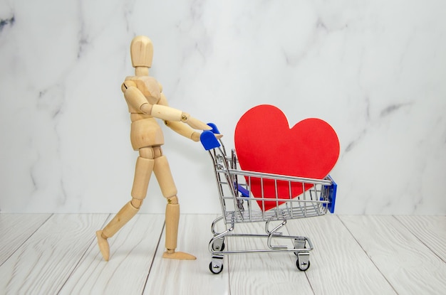 Figurine en bois de l'homme et du caddie avec un grand coeur rouge à l'intérieur. cadeau concept, saint valentin, amour