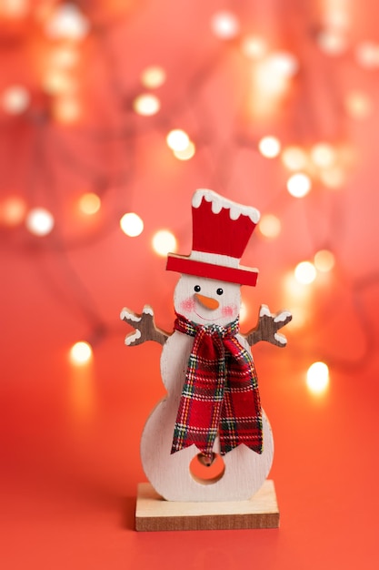 Figurine d'un bonhomme de neige mignon joyeux sur un fond rouge de Noël bokeh rougeoyant Photo de haute qualité