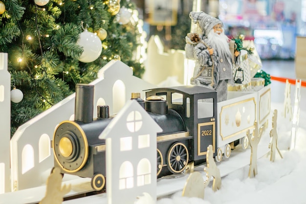 Figurine jouet du Père Noël en train avec inscription 2022 et silhouettes de maisons sur fond d'arbre de Noël