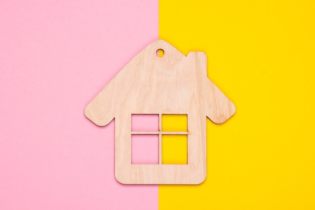 Figurine de maison en bois ou porte-clés sur fond de couleur pastel. Vue de dessus