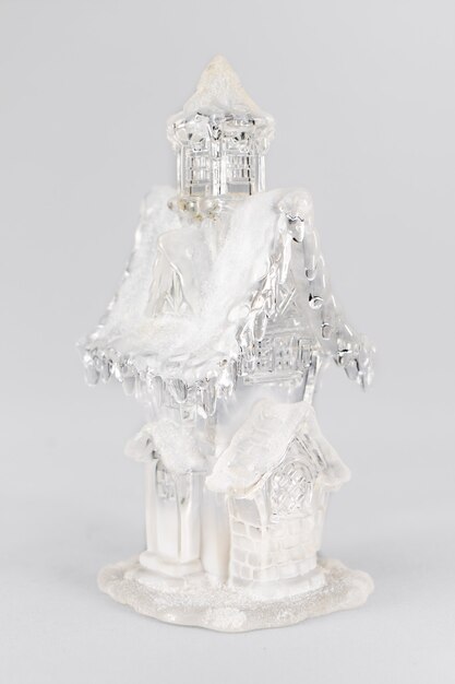 Figurine de Noël en verre d'une maison avec de la neige. Composition de Noël sur fond gris. Concept de Noël à la maison doux à la maison