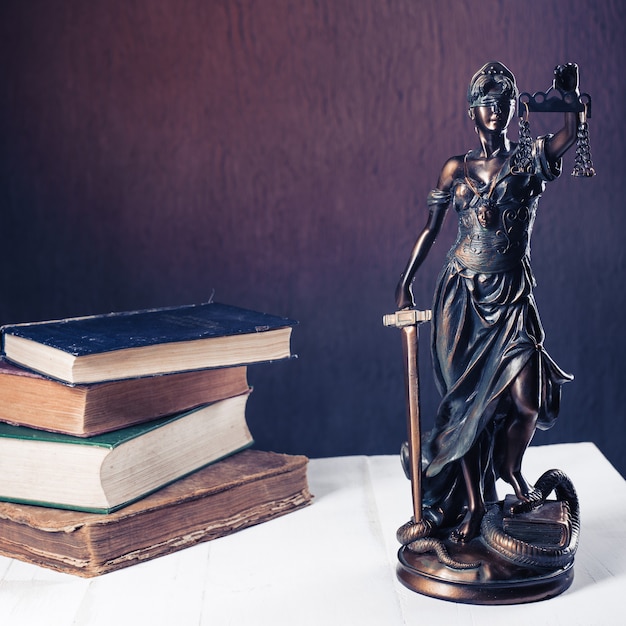 La figurine Themis se dresse sur une table en bois blanche à côté d'une pile de vieux livres. Avocat à la balance Business Concept. - Image