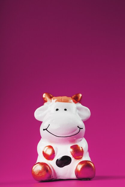 Figurine d'une vache sur fond rose, espace libre pour le texte