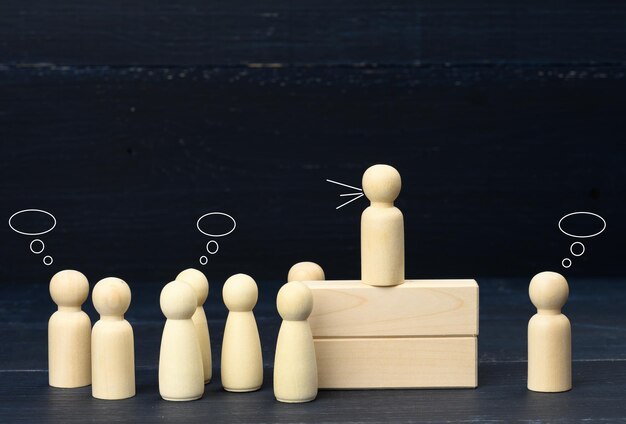 Photo figurines en bois d'hommes sur un fond bleu discours public concept de leadership et de discussion l'équipe s'unit autour d'une idée de coopération