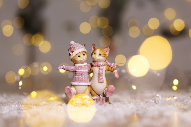 Figurines décoratives d'un thème de Noël. Figurine de jolis chats étreignant vêtus d'un pull, d'une écharpe et d'un bonnet tricotés