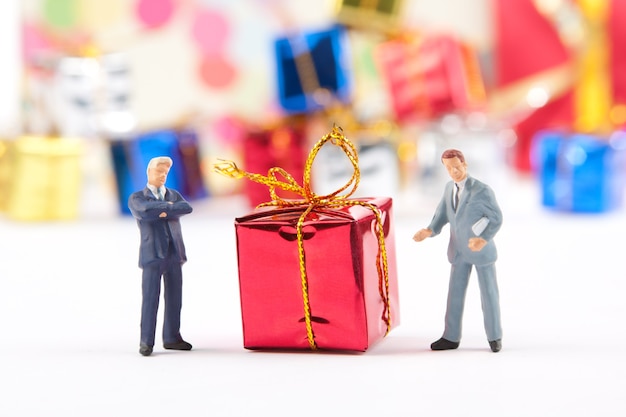 Figurines miniatures de deux hommes d'affaires avec cadeau de Noël rouge