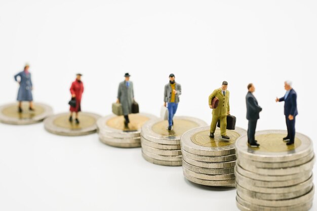 Figurines sur une pile de pièces sur un fond blanc