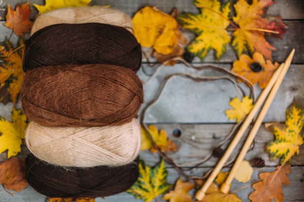 Le fil est beige, marron. Le tricot comme passe-temps. Accessoires pour tricoter. Fils parmi les feuilles.