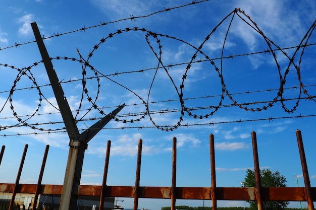 Fil de fer barbelé contre le ciel bleu Le fil de fer barbelé est un fil ou une étroite bande de métal avec des pointes pointues Dispositif de barrières Le concept de liberté protection de la propriété violence emprisonnement