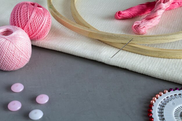 Fil rose et accessoires pour broderie sur fond gris