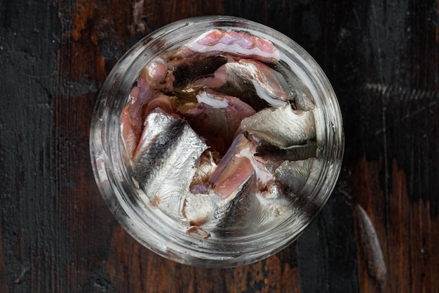 Filet d'anchois salés marinés, dans un bocal en verre, sur la vieille table en bois sombre