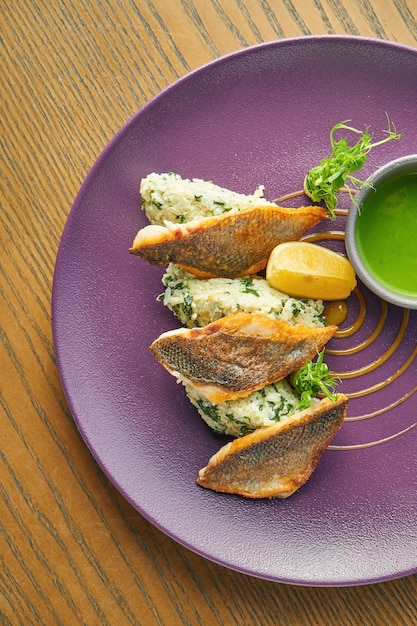 Filet de bar frit pané avec garniture de riz sur une assiette violette sur une table en bois. Restaurant servant. Gros plan, mise au point sélective