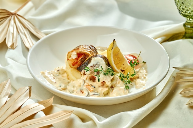 Filet de bar frit avec sauce aux champignons et purée de pommes de terre dans une assiette blanche sur une nappe