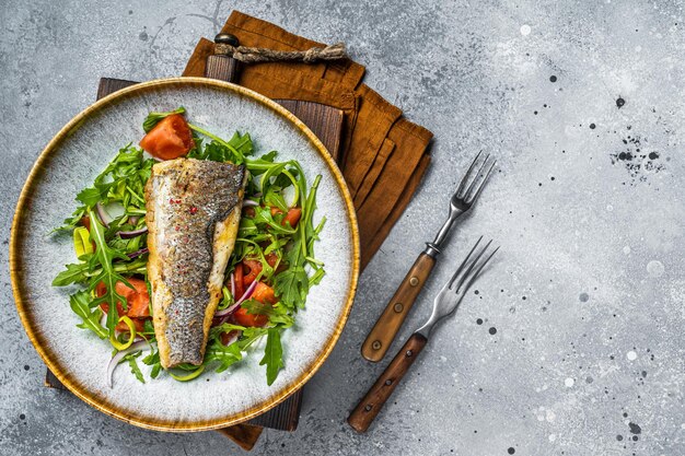 Photo filet de bar frite avec salade de légumes poisson dicentrarchus arrière-plan gris vue supérieure espace de copie