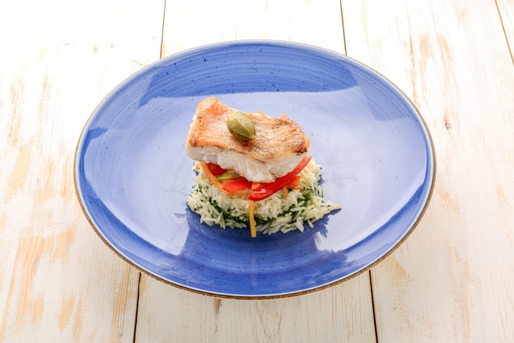 Photo filet de bar grillé. riz bouilli avec des légumes sur une plaque de couleur.