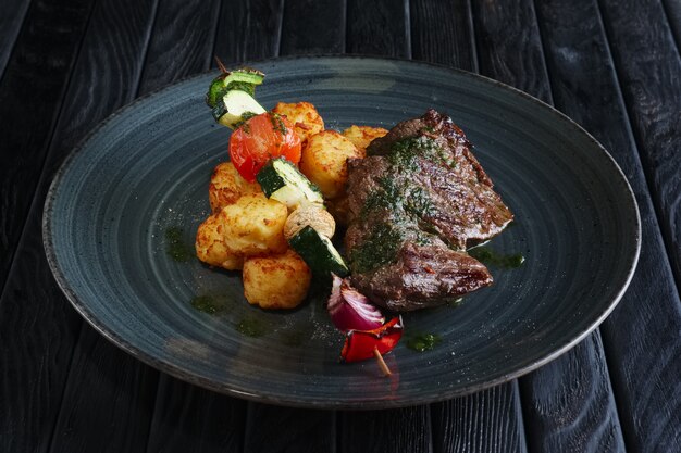 Filet de bœuf grillé juteux avec pommes de terre, champignons, courgettes, tomates, poivrons et oignons rouges sur brochette en bois