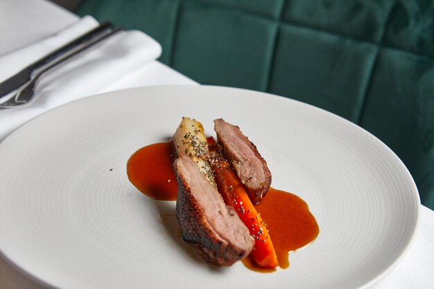 Filet de canard aux légumes à la sauce aigre-douce sur une vue de dessus de plaque blanche