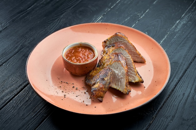 Filet de dinde grillé sur charbon de bois, servi avec sauce rouge dans une assiette sur fond de bois sombre. Kebab de dinde