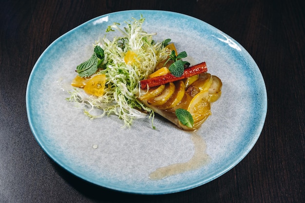 filet de flétan avec garniture de fruits sur une assiette en céramique bleue