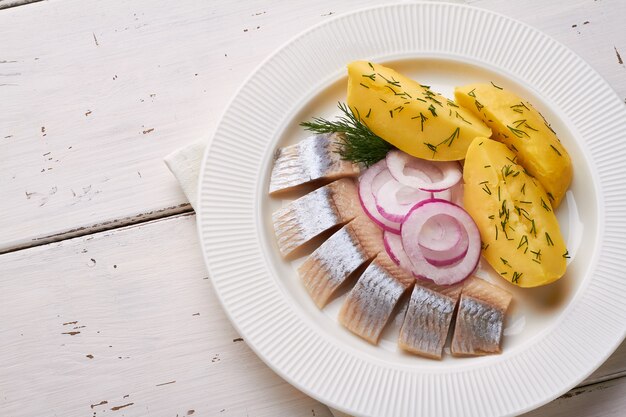 Filet de hareng salé tranché avec plaque blanche de pomme de terre oignon rouge