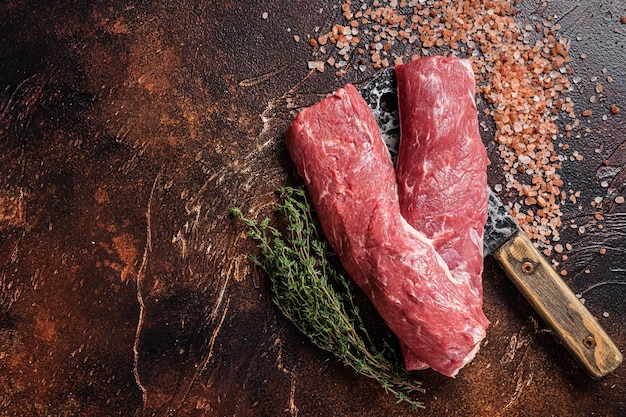 Filet de longe d'agneau non cuit, viande crue de mouton sur couperet de boucher. Fond sombre. Vue de dessus. Espace de copie.