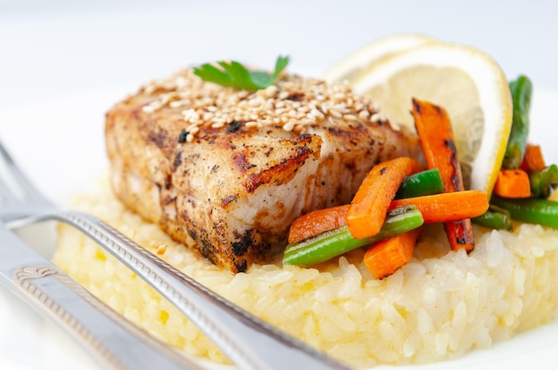 Filet de perche frit avec du riz et des légumes sur une plaque blanche avec des couverts sur un fond blanc gros plan isolé