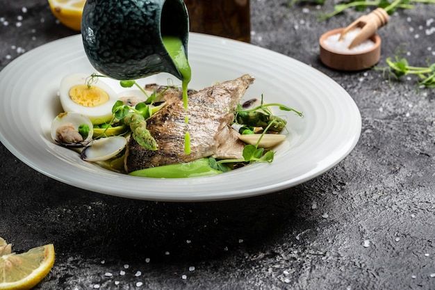 Filet de poisson au charbon avec asperges vertes, fruits de mer, petits pois, asperges et sauce à la crème