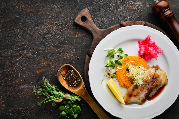 Filet de poisson au four avec purée de patates douces. Dans l'assiette. Vue de dessus. Espace libre pour votre texte. Style rustique.