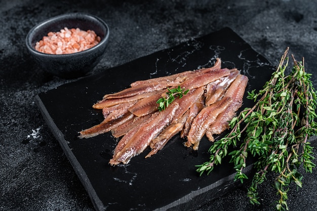 Filet de poisson aux anchois à l'huile d'olive. Fond noir. Vue de dessus.