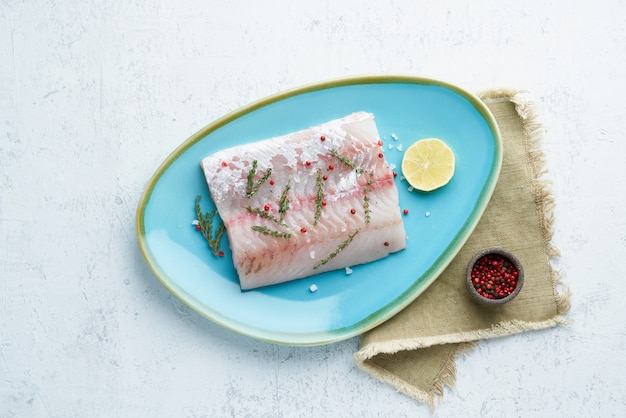 Filet de poisson doré jaune cru sur une plaque bleue sur blanc