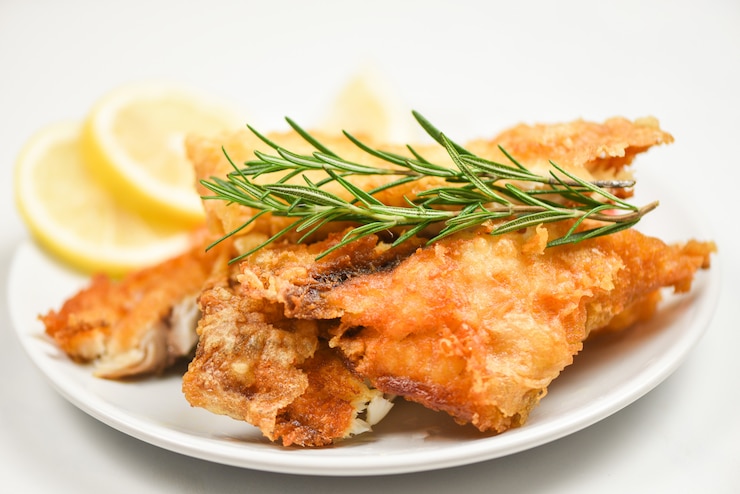 Photo filet de poisson frit tranché pour steak ou salade cuisson des aliments aux herbes épices romarin et citron - filet de tilapia croustillant au poisson servi sur plaque blanche