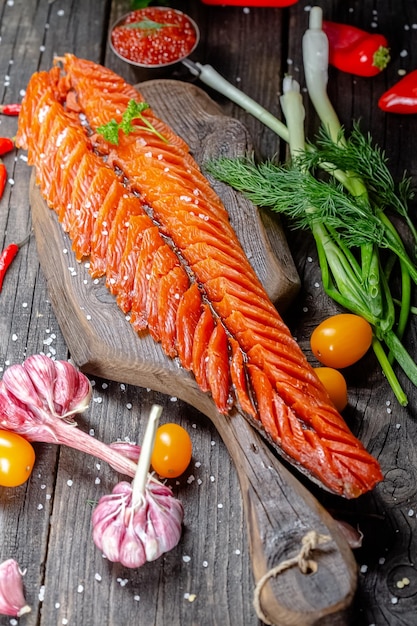 filet de poisson rouge tranché fumé en tranches se trouve sur une planche à découper rustique vintage et une table, des cordes