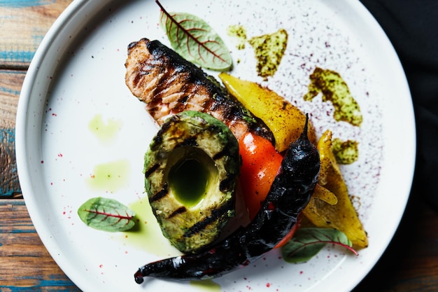 Filet de poisson saumon grillé avec légumes et avocat sur la plaque close up