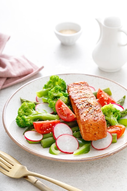 Filet de poisson saumon grillé et salade de légumes aux radis tomate poivron vert brocoli et asperges