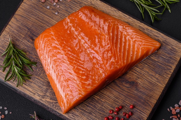 Filet de poisson saumon rouge cru avec sel, épices et herbes sur fond de béton foncé