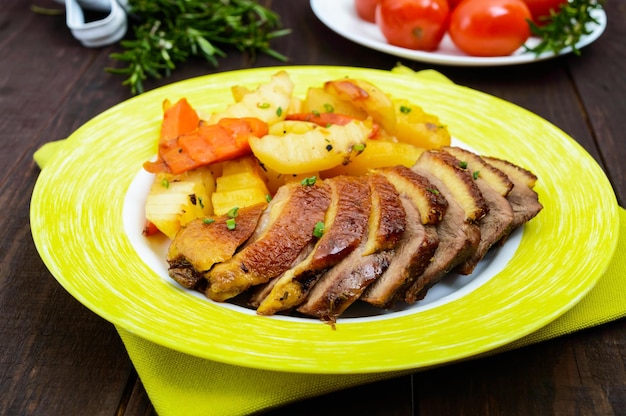 Filet de poitrine d'oie rôti aux pommes de terre de style rustique sur une assiette sur un fond en bois foncé