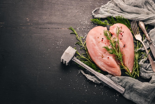 Filet de poitrine de poulet cru au romarin et aux épices sur un fond en bois noir Vue de dessus Espace libre pour le texte