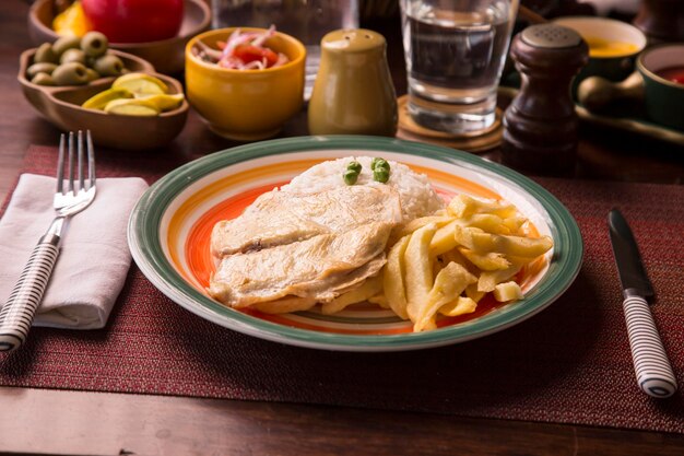 Filet de poitrine de poulet frites cuisine traditionnelle péruvienne mise en place table en bois