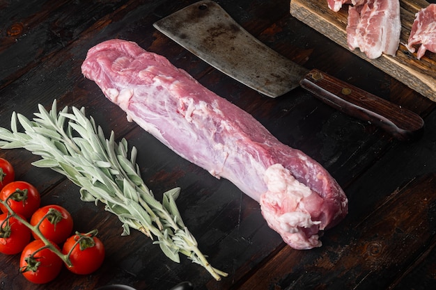 Filet de porc cru avec des ingrédients et des herbes sertie de vieux couteau couperet de boucher, sur la vieille table en bois sombre