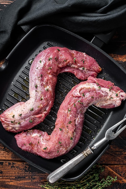 Filet de porc cru prêt pour la cuisson de la viande crue dans une poêle à griller avec des herbes et de l'huile d'olive Fond en bois Vue de dessus